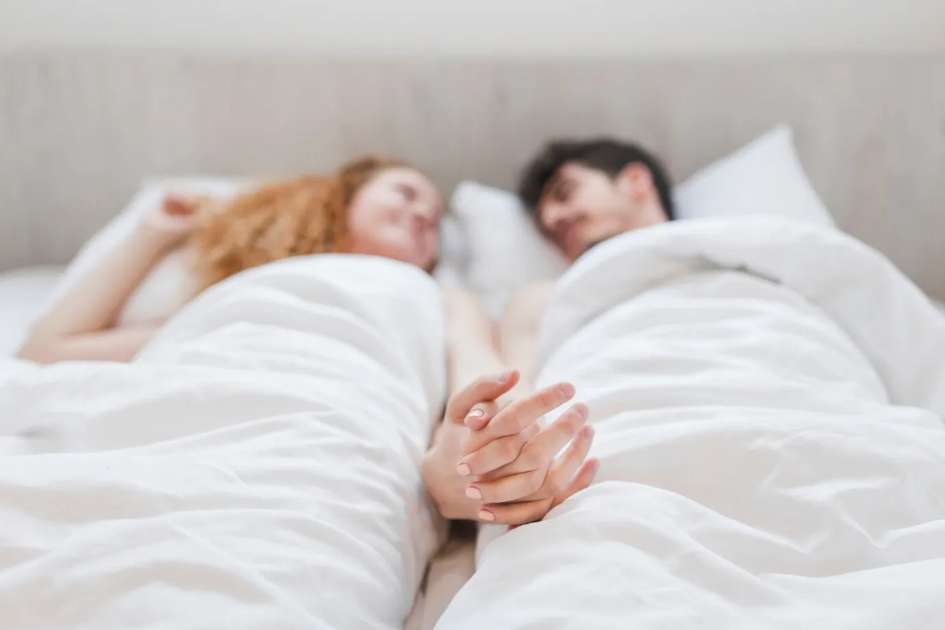 couple-holding-hands-while-lying-bed_23-2147909503