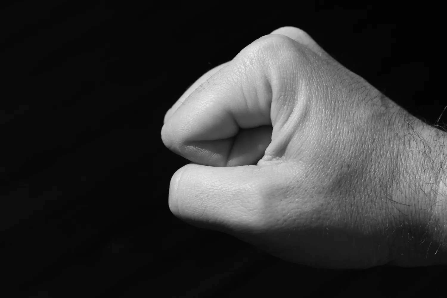 grayscale-shot-fist-person-black-background